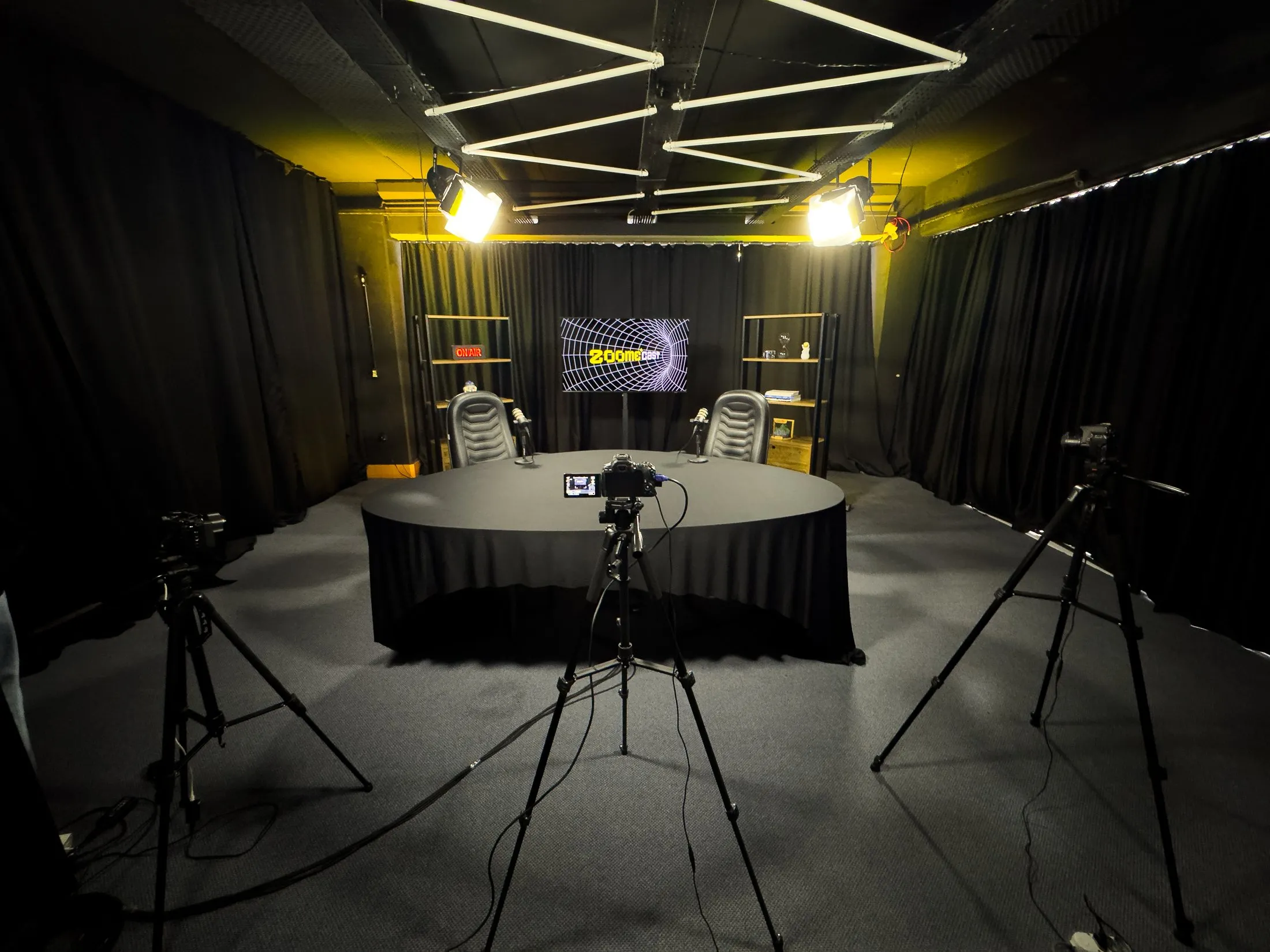 Set de podcast do estúdio ZOOME com mesa redonda, câmeras e iluminação
